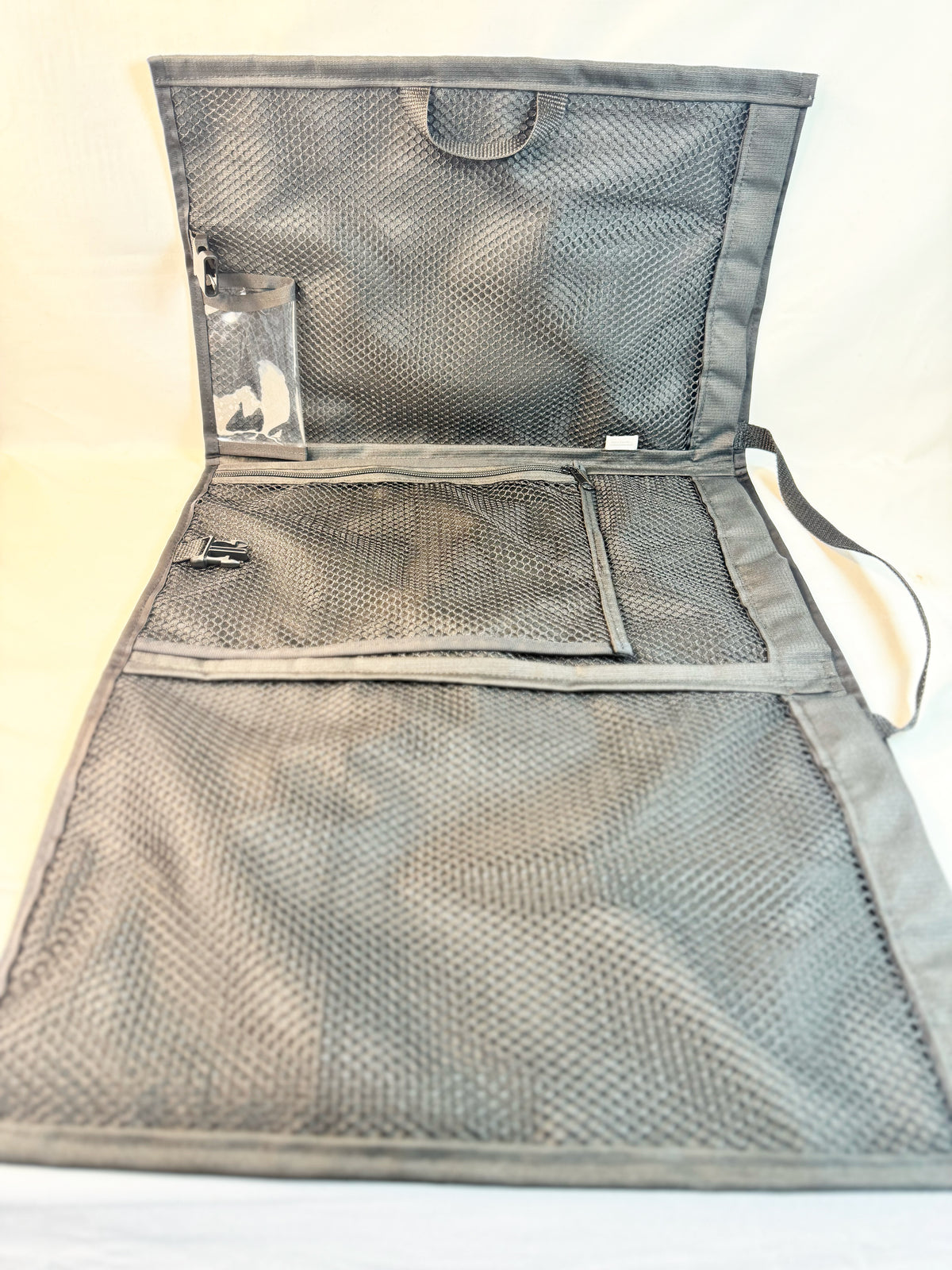 Gray foldable sports bag with mesh compartments and zipper closure designed for uniforms and gear storage.