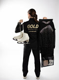 Person holding ice skates and a decorative bag with 'Gold Medalist' branding on a white background