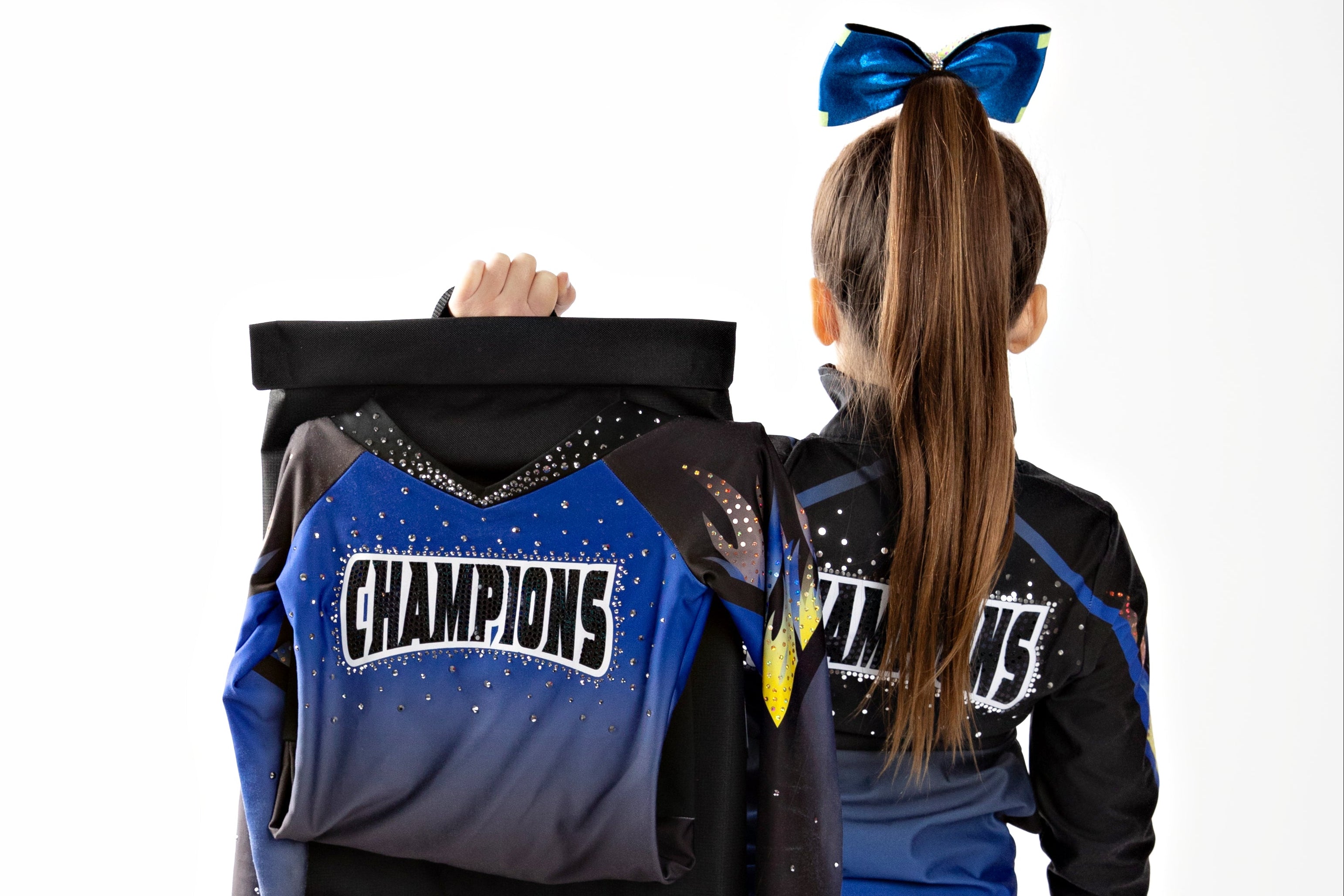 Foward facing cheerleader with a bow holding a bag with a cheerleading uniform