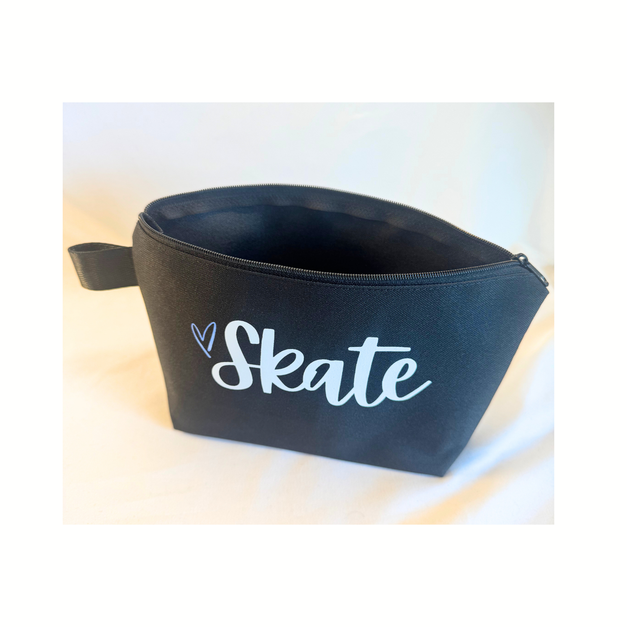 Black zippered fabric bag with white "Skate" lettering and a small heart icon on the front.