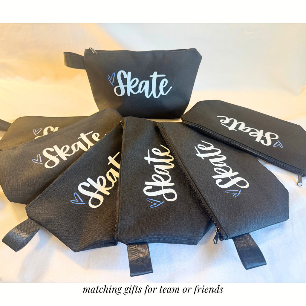Black rectangular zippered bags with wrist straps, each featuring white cursive "Skate" text and a small heart detail.