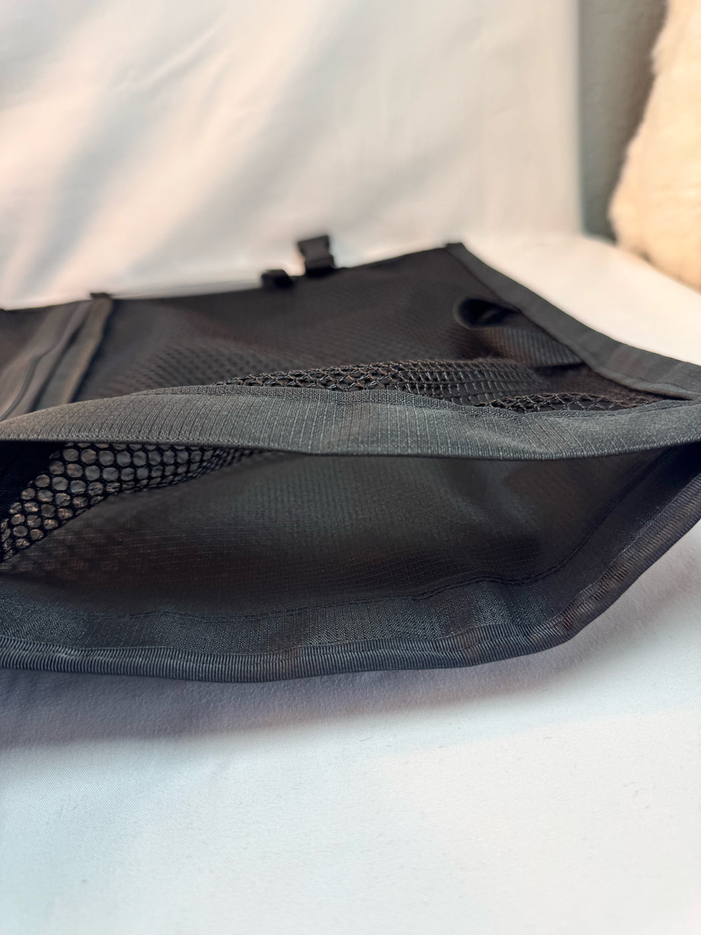 Black mesh sports bag with zipper and fabric trim, designed for carrying uniforms and gear.