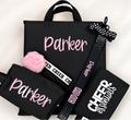 Black cheer backpack set with pink personalized name, pom pom keychain, bow hair tie, and cheer emergency kit pouch.