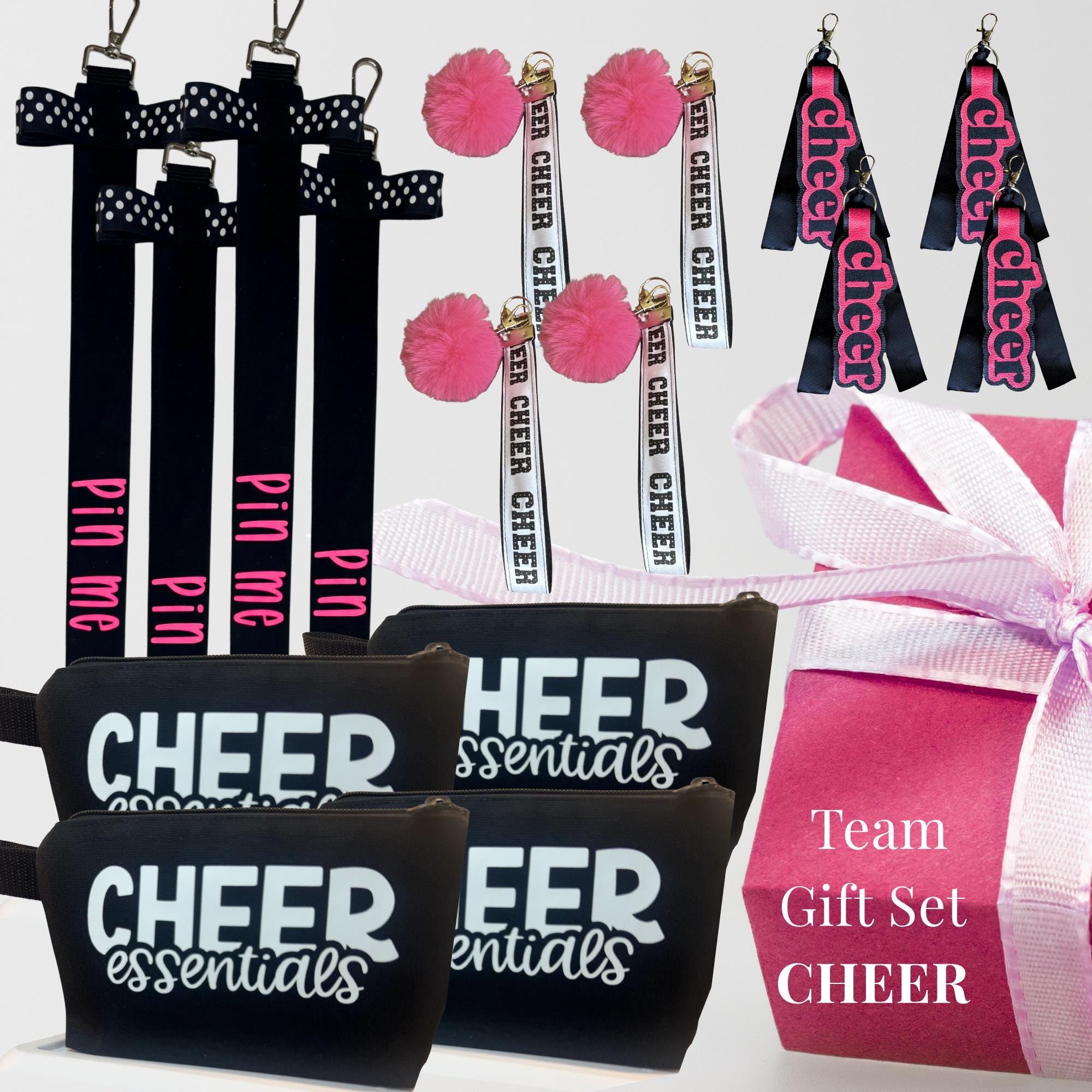 Set of black cheer-themed wristlets and keychains with pink, white, and black accents, plus a pink gift bag with ribbon.