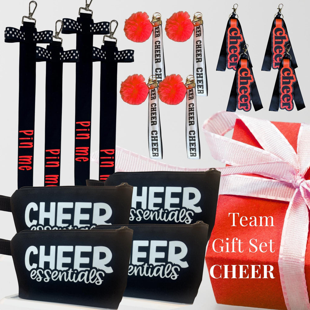 Black and white cheer wristlets, black zipper pouches labeled "Cheer Essentials," red pom-pom keychains, and black cheer bag