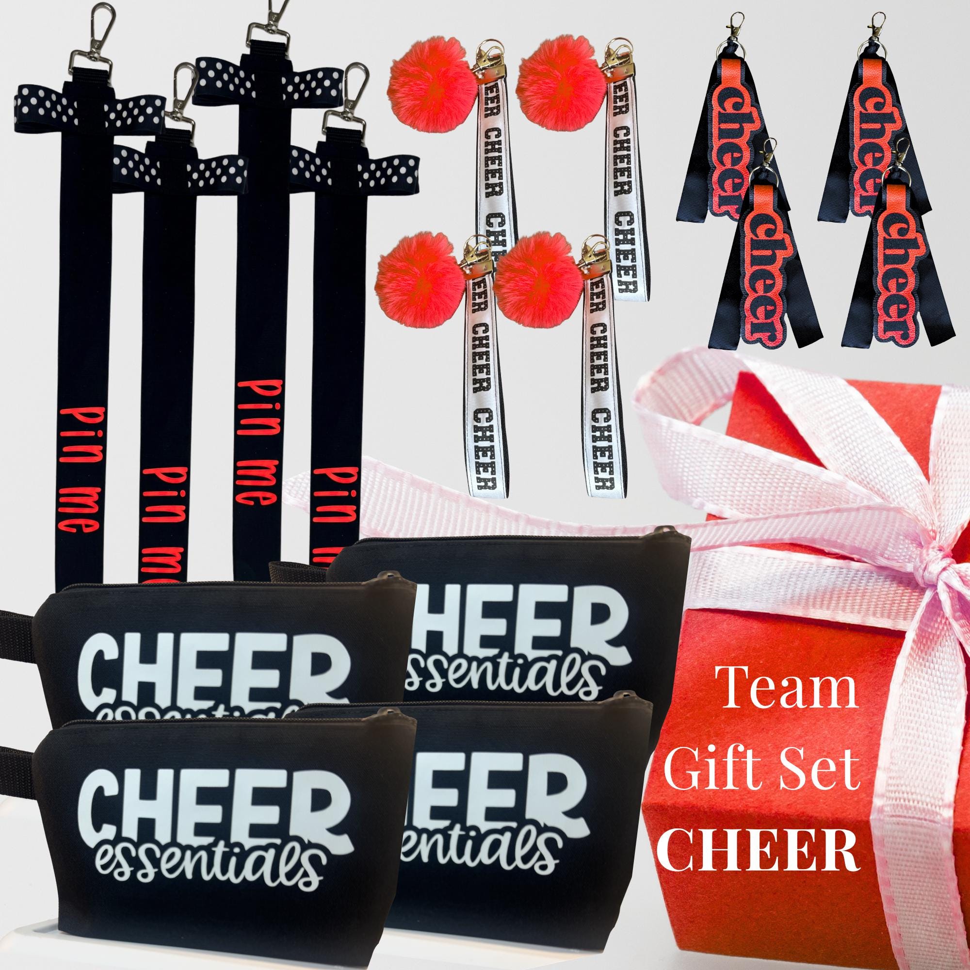 Black and white cheer wristlets, black zipper pouches labeled "Cheer Essentials," red pom-pom keychains, and black cheer bag