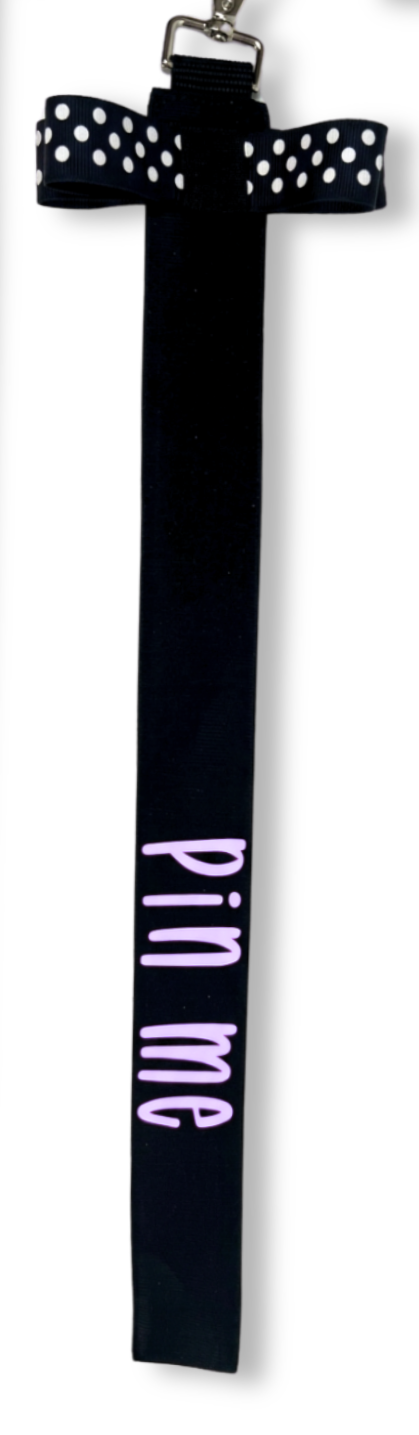 Black cotton ribbon with white polka dots bow and pink "pin me" text, metal clip attachment.